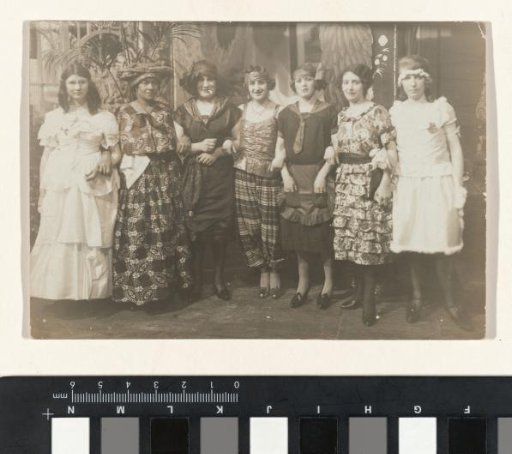 Group portrait of seven women in costume at a masked ball