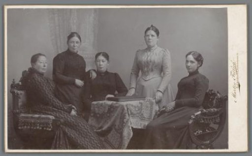Portrait of five unknown women around a table with an album
