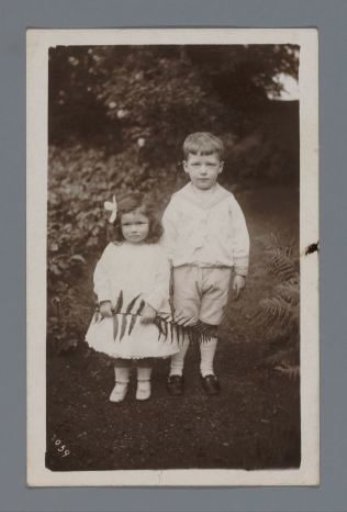 Portrait of an unknown boy and girl with a fern branch in a forest