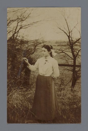 Portrait of an unknown woman in front of a fence in a meadow