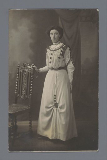 Studio portrait of an unknown woman next to a chair