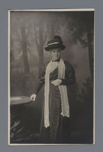 Studio portrait of an unknown elderly woman next to a chair