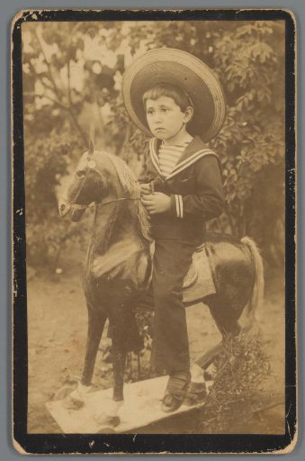 Portrait of an unknown boy sitting on a toy horse