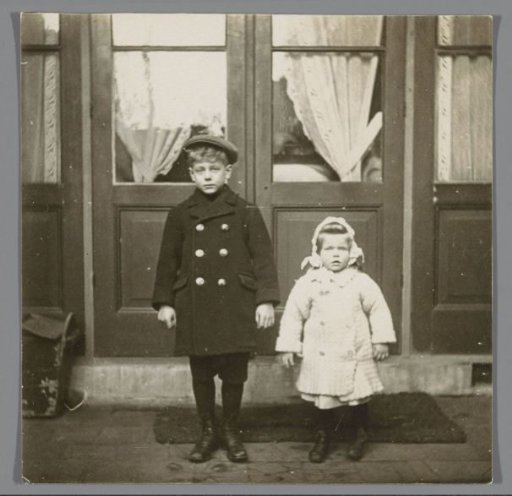 Portrait of two unknown children, standing in front of a door