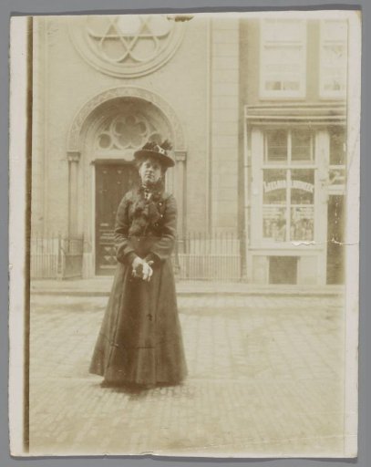 Portrait of an unknown young woman on the street, standing in front of a church and a library