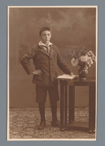 Studio portrait of an unknown boy beside a table