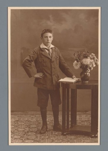 Studio portrait of an unknown boy beside a table