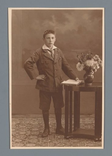 Studio portrait of an unknown boy beside a table