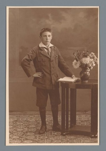 Studio portrait of an unknown boy beside a table