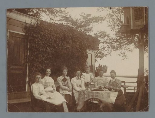 Group portrait of seven unknown women in a garden by the water