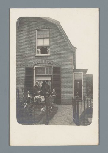 Group portrait of four unknown persons in front of a residence