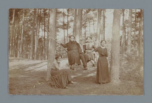 Group portrait of four unknown women and a man around a hammock in a forest
