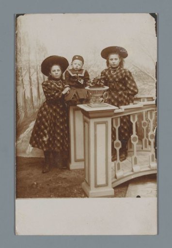 Studio portrait of two unknown girls in dresses with a child