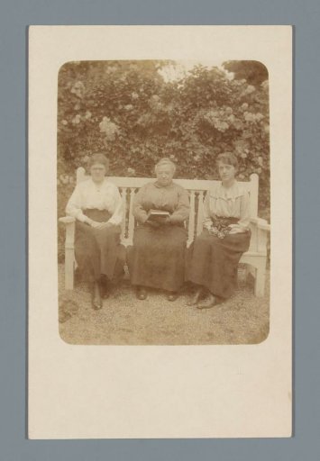 Portrait of three unknown women on a bench in a garden