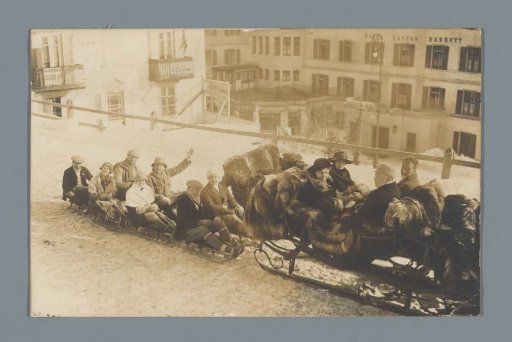 Seven unknown persons on wooden sleds behind a sleigh (presumably) at St. Moritz