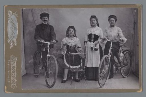 Group portrait of four unknown girls in traditional dress with bicycles
