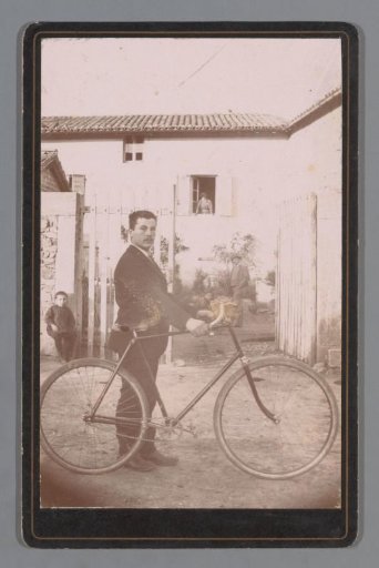 Portrait of an unknown man with a bicycle in front of a house