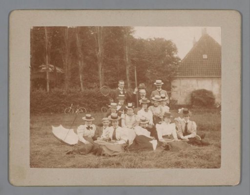 Group portrait of an unknown company with tennis rackets in a meadow