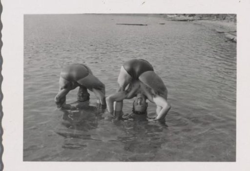 Two unknown men on a beach with their heads between their legs