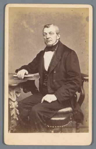 Portrait of an unknown man, seated at a table with a number of books under his hand