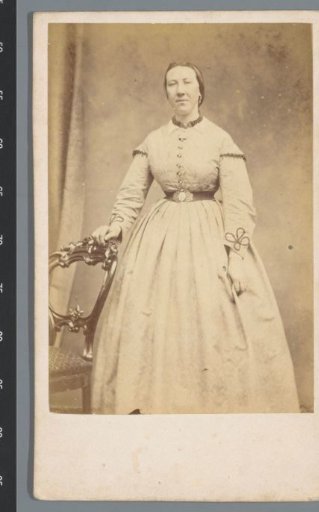 Portrait of an unknown woman, standing beside a chair