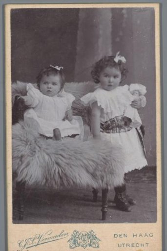 Portrait of two unknown girls by a chair
