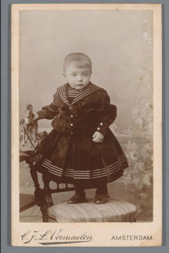 Portrait of an unknown child, standing on a chair with a toy in hand
