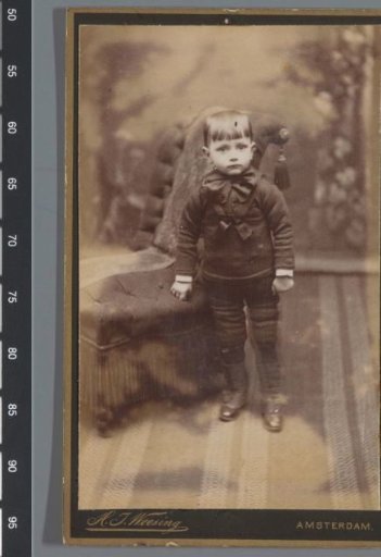 Portrait of an unknown boy, standing next to a chair