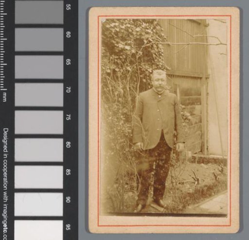 Portrait of an unknown man, standing in front of a fence