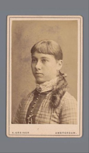 Portrait of an unknown girl, standing beside a table with an album in her hands
