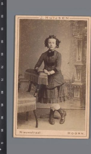 Portrait of an unknown girl, standing beside a chair