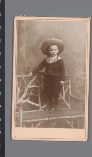 Portrait of an unknown boy wearing a hat, standing on a bench