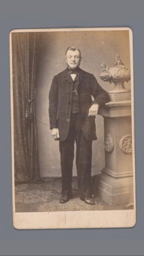 Portrait of an unknown man, standing beside a pedestal