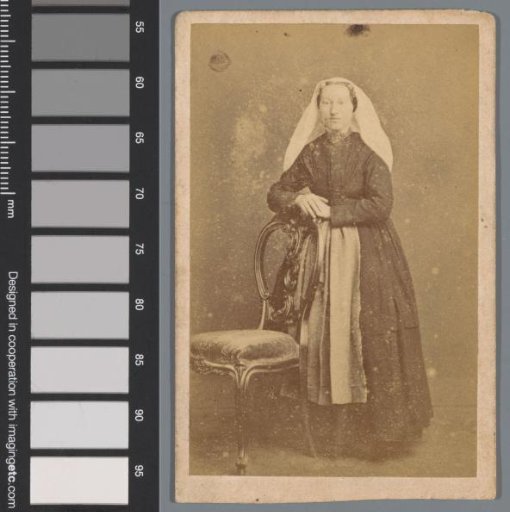 Portrait of an unknown woman behind a chair