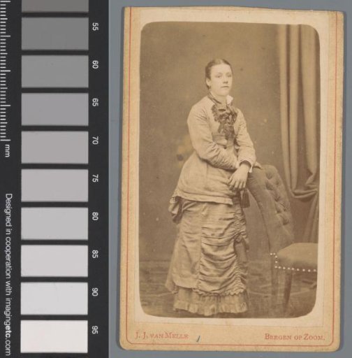 Portrait of an unknown young woman behind a chair