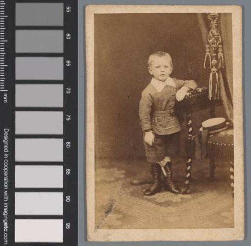 Portrait of an unknown boy beside a chair