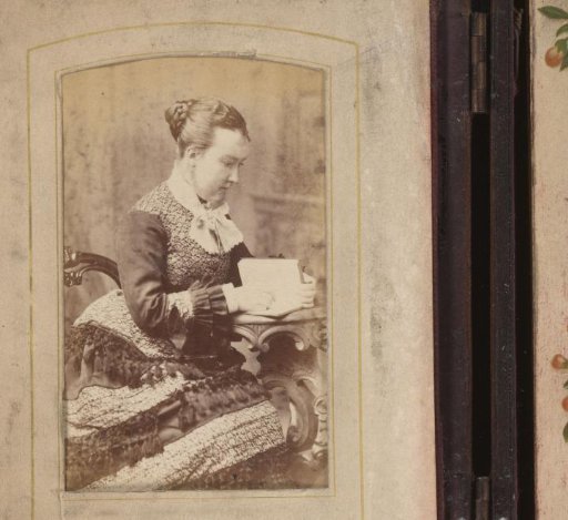 Portrait of a woman with an open book in hand, seated at a table