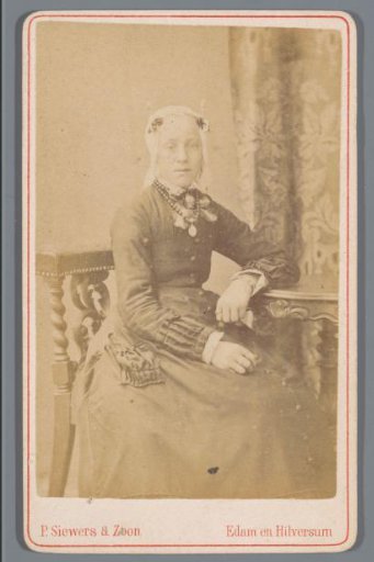 Portrait of an unknown woman wearing a cap, seated at a table