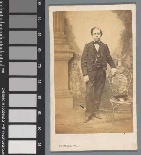 Portrait of an unknown boy beside a chair