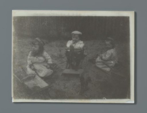 Three toddlers in a garden with toys, a rocking horse and wheelbarrows with a shovel, probably the twins Ad (left) and Johanna (right), and Han (middle) van der Kop