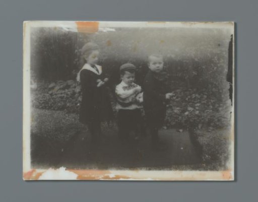 Three toddlers in a garden playing with a ribbon, probably the twins Ad (middle) and Johanna (left) and Han (right) van der Kop