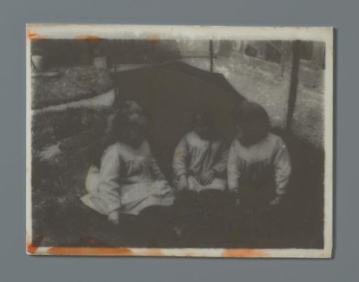 Three toddlers in a garden sitting under an umbrella, probably the twins Ad (right) and Johanna (left) and Han (middle) van der Kop