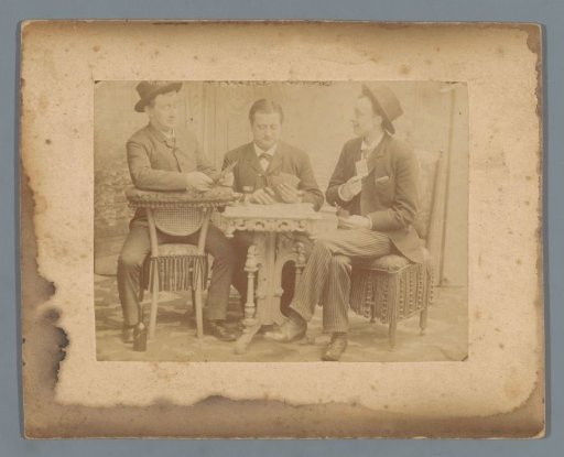 Three men playing cards around a table in an interior