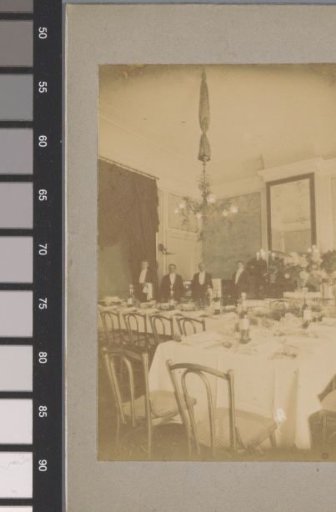 Four waiters posing behind a set table