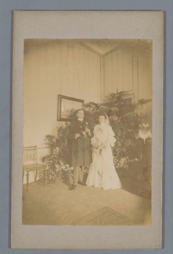 Bride and groom posing in front of plants and a painting