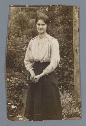 Portrait of an unknown woman in a garden with flowers in her hand