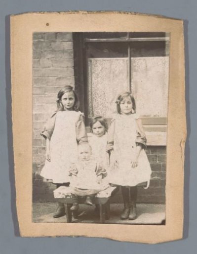 Portrait of four unknown children in front of a house