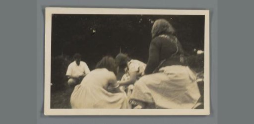 Three women in a garden and a man photographing them
