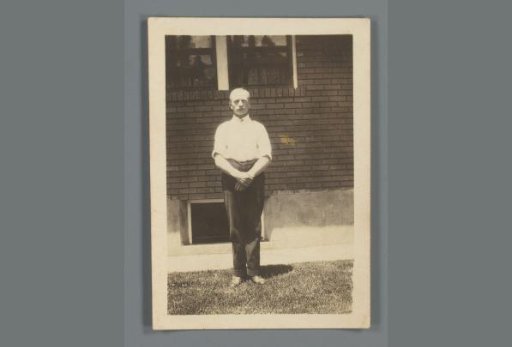 Portrait of an unknown man standing in front of a house