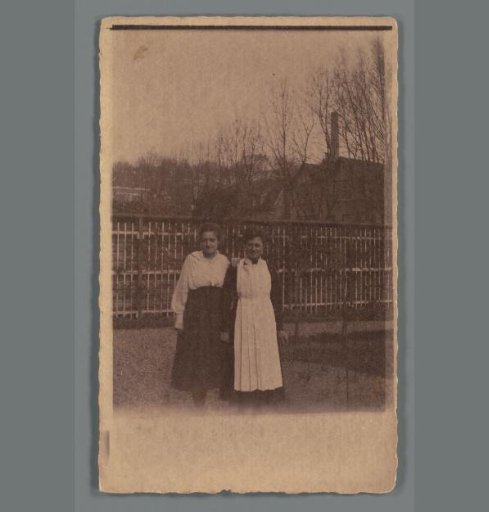 Portrait of two unknown women in front of a fence